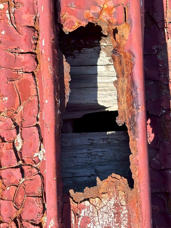 津市で板金屋根が錆びて穴があいてしまい下地の木が露出している様子